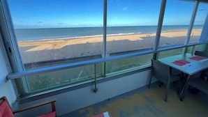 A room with large windows overlooking a beach. - PLEINE MER Front de Mer - 1st Et. Elevator - 4P - Parking - Wifi - Linen Ok (Courseulles-sur-Mer)