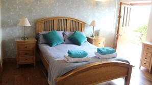 A bedroom with a wooden bed, two nightstands, and a wooden wardrobe. - Henllys Estate B&B (Llandovery)