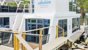 Een witte boot met 'Dolphins Vacation Rentals' branding, airconditioning en een dek met zitplaatsen.