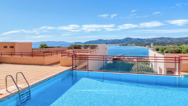 Una piscina en la azotea con vistas despejadas al mar y montañas lejanas.