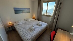 Una habitación de hotel con cama, escritorio, silla, lámpara y un cuadro en la pared.