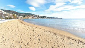A sandy beach with footprints, a clear sky, and buildings in the background. - Exceptional sea view in Lavandou (Le Lavandou)