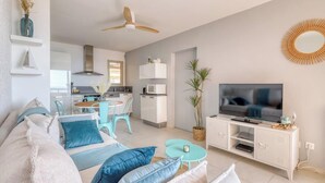 A modern living room with a sofa, TV, and dining area. - Exceptional sea view in Lavandou (Le Lavandou)