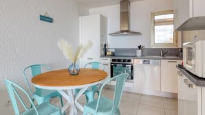 A modern kitchen with white cabinets, a stainless steel range hood, and a window above the sink. - Exceptional sea view in Lavandou (Le Lavandou)