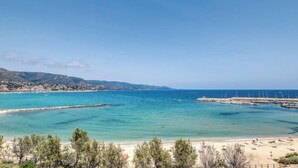 Une vue sur la côte, avec une plage, une eau d’un bleu limpide et une ville qui se dessine à l’horizon.