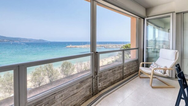 Un balcon avec vue sur la mer et une chaise blanche.