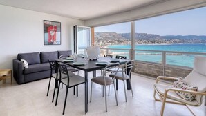 Un balcon avec une table et des chaises pour prendre les repas, un canapé et une vue sur la mer et les montagnes.