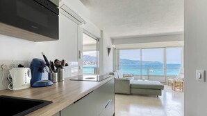 Une cuisine moderne avec vue sur la mer, un coin repas offrant également une vue, et un salon avec un canapé et une table.