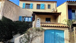 A two-story building with a stone facade, blue shutters, and a tiled roof.