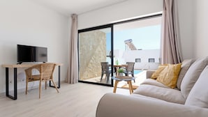 Een moderne woonkamer met een flatscreen televisie, een bank, een eettafel en een balkon met een zwembad.