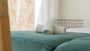 Een kamer met een bed, een kussen en een handdoek.