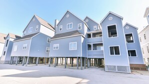 A row of blue waterfront houses with multiple stories, each featuring a balcony and a front porch.