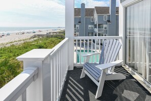 A balcony with a view of the beach, a pool, and a building in the background. - Oceanfront 2 BR Condo with a Shared Pool! Cape Coddages I 203 (Surfside Beach)