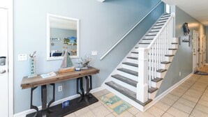 A staircase with white railings and a wooden console table with a mirror above it. - 2nd Row 4 BR Beach House with a Shared Pool! - Chubby's Anchor (Surfside Beach)