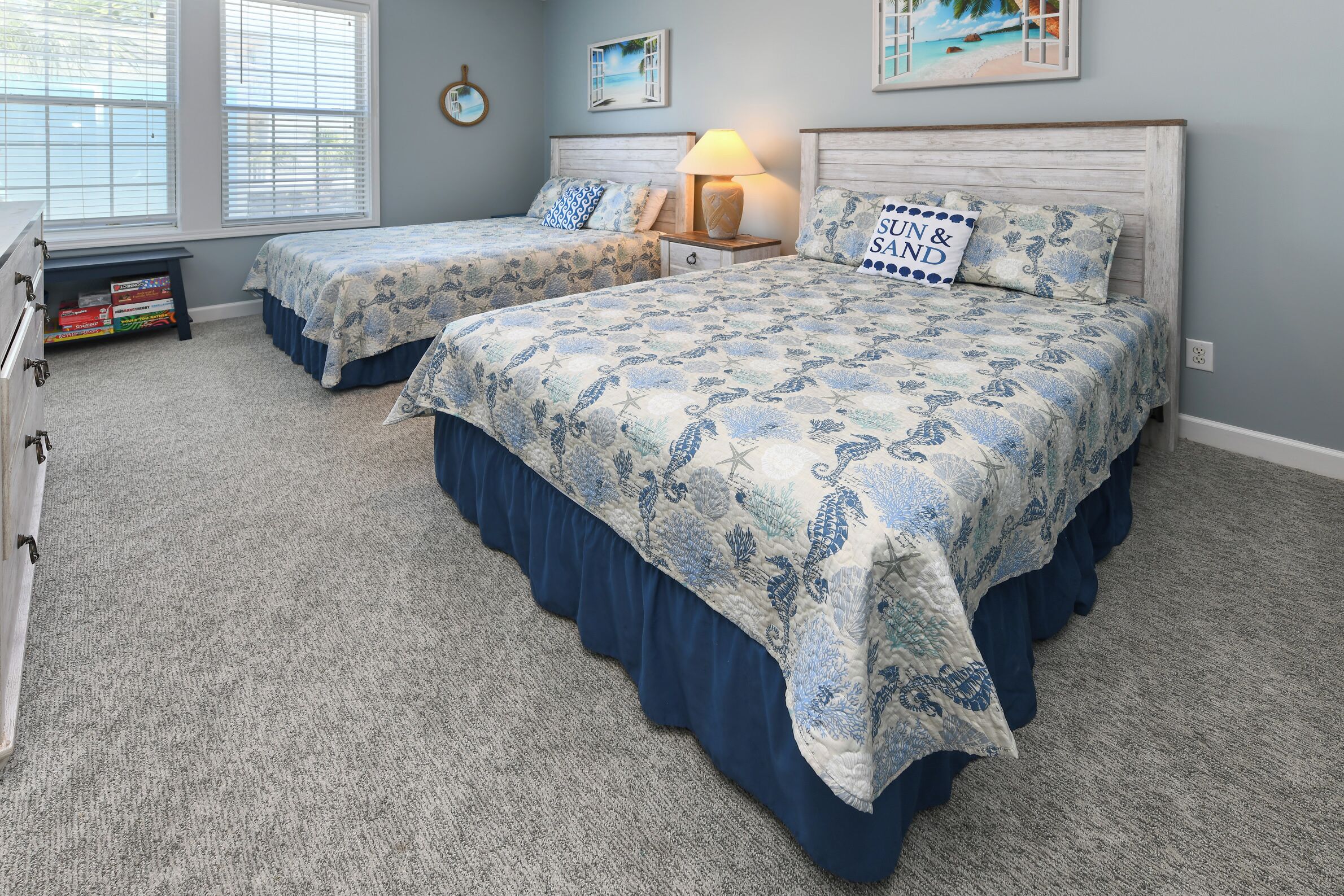 A bedroom with two beds, a nightstand, a lamp, and a bookshelf.