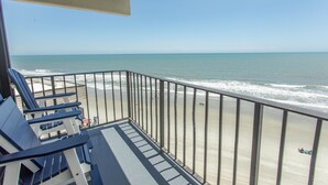 A balcony with a view of the beach and ocean.