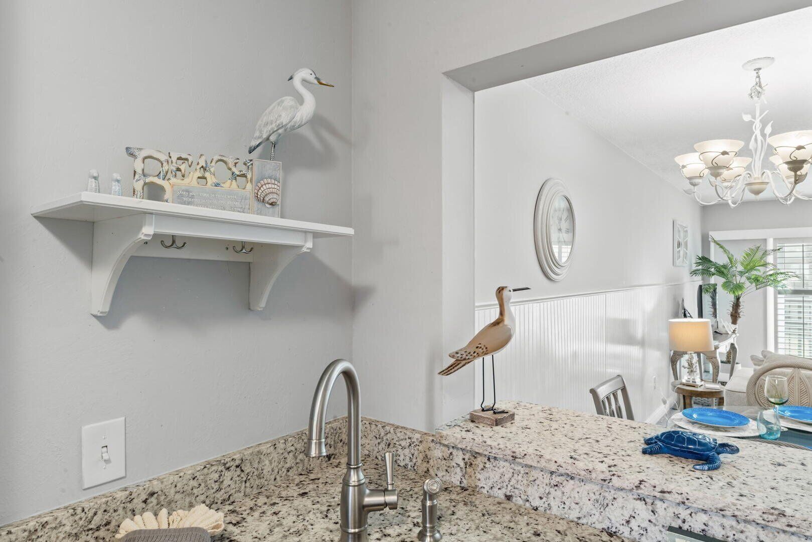A bathroom with a granite countertop, a sink, a mirror, a towel rack, and decorative bird figurines.