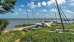 A marina with several sailboats docked, a wooden pier extending into the water, and lush greenery surrounding the area. - Mystic Sands I Steps To Beach I Free Activities 2 Bedroom Condo (St. Augustine)