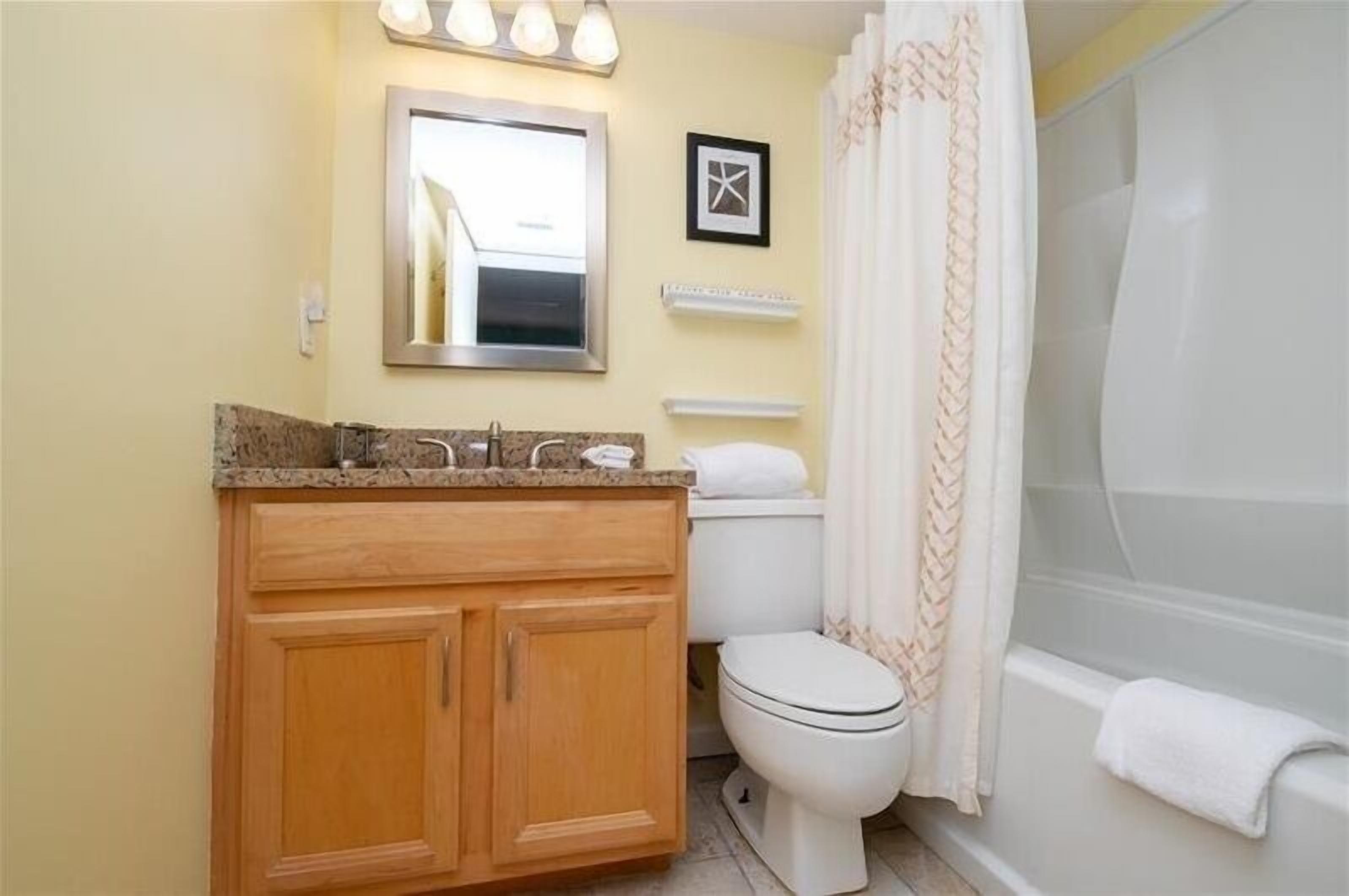 A bathroom with a wooden vanity, a toilet, and a bathtub.