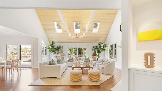 Un salon spacieux avec un haut plafond, de grandes fenêtres et un coin repas.