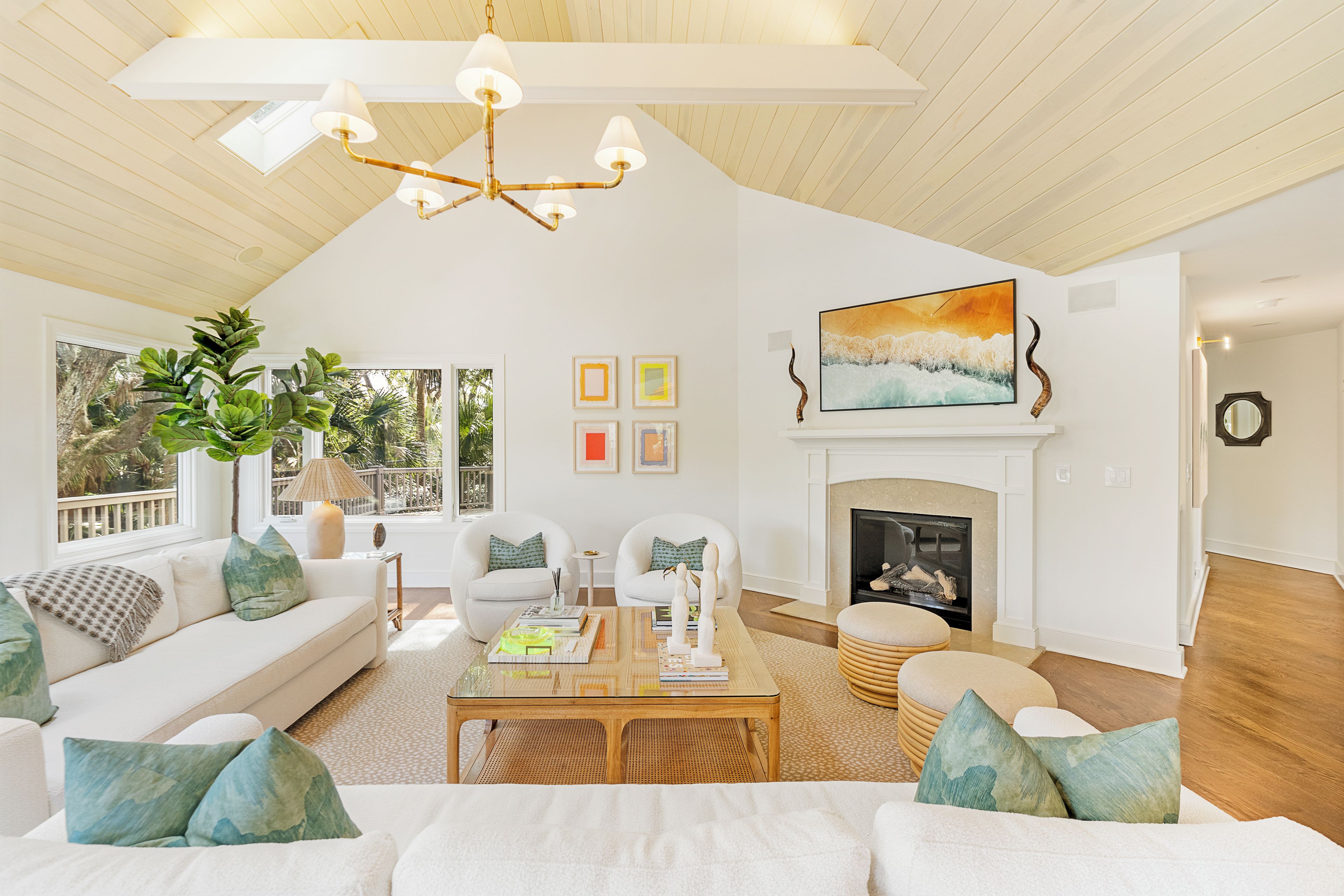 A spacious living room with a high ceiling, a fireplace, and a large window overlooking a balcony.