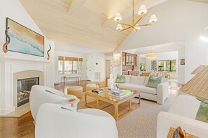 A spacious living room with a fireplace, a large chandelier, and a view of the outdoors. - Stunning view in great Vanderhorst area location (Kiawah Island)