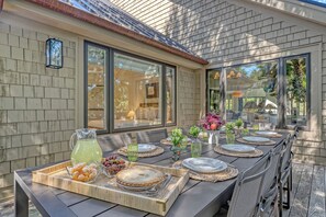 An outdoor dining area with a long table set for a meal, including plates, glasses, and a pitcher of lemonade. - Stunning view in great Vanderhorst area location (Kiawah Island)