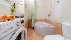 Un baño pequeño con lavadora, lavamanos, inodoro y ducha.