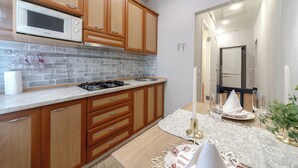 Una cocina moderna con armarios de madera, microondas, estufa a gas y salpicadero de azulejos.