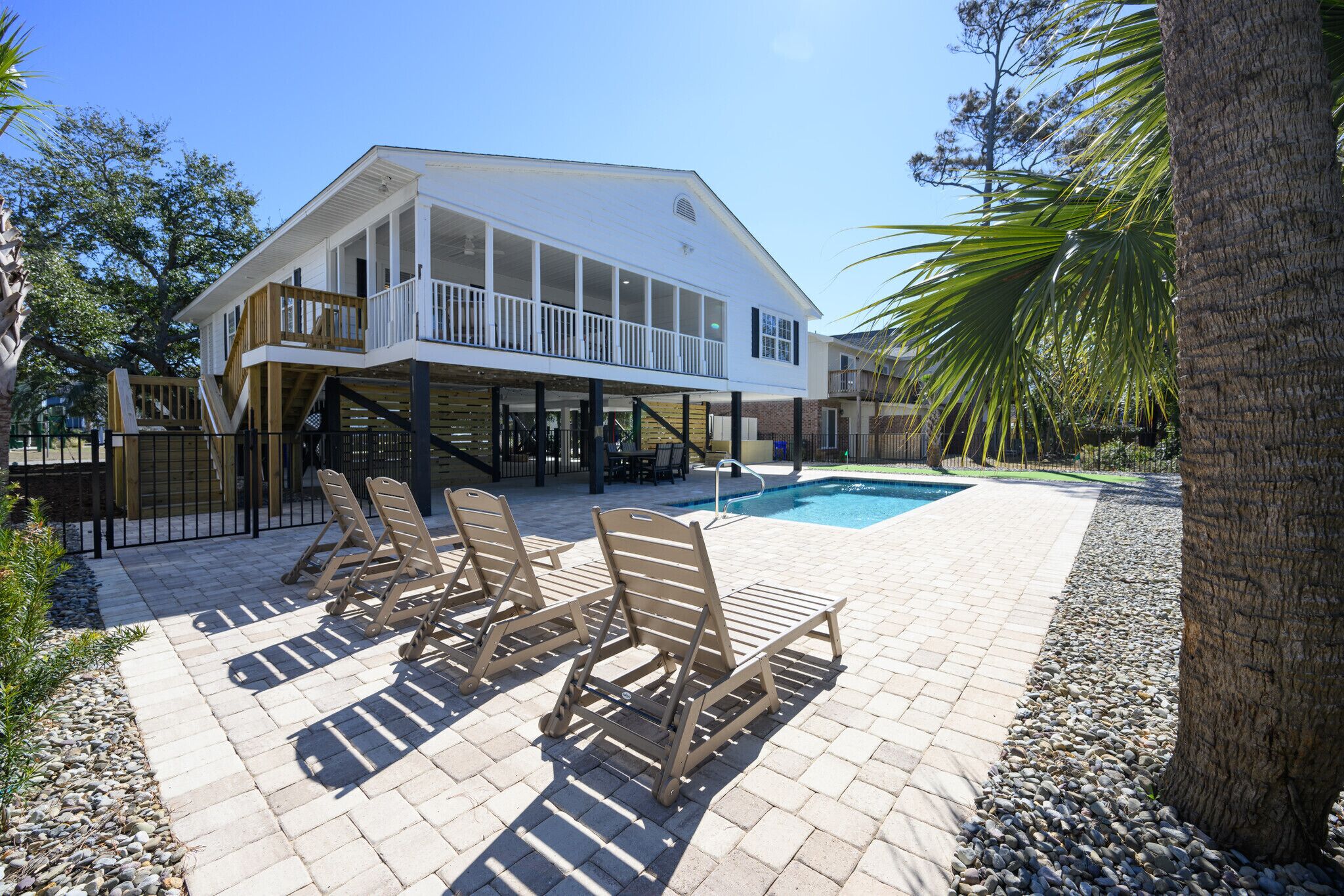 A two-story house with a balcony, a swimming pool, and outdoor seating.