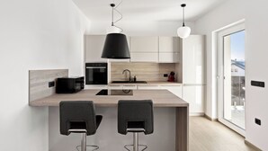 A modern kitchen with a central island, two bar stools, and pendant lighting. - Kristal 2,5 bed Lux Apartment in Rogaška (Šmarje pri Jelšah)