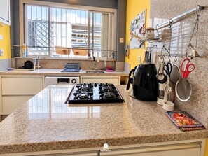 Une cuisine équipée d’une cuisinière à gaz, d’une machine à café et de divers ustensiles de cuisine.