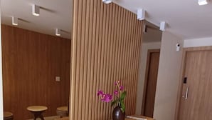 A modern interior with a wooden partition, a small wooden table, and a vase with purple flowers. - Ap Punta Cana em Balneário Camboriú - SC (Balneário Camboriú)