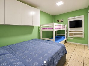Une chambre avec des lits superposés, une télévision et un placard.