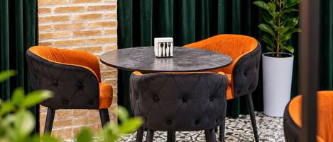 A round table with a black top, surrounded by four chairs with black and orange upholstery.