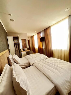 A hotel room with a bed, a desk, a TV, and a wardrobe. - Badyan Hotel (Bukhara)