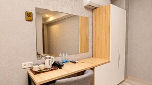 Ett hotellrum med ett skrivbord i trä, en spegel, en skylt med texten ”Rökning förbjuden”, en vattenkokare, en telefon och en stol.