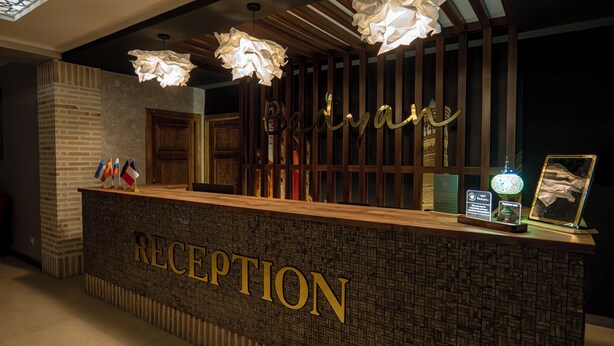 A reception desk with a brick wall, wooden paneling, and a sign that reads "RECEPTION". - Badyan Hotel (Bukhara)