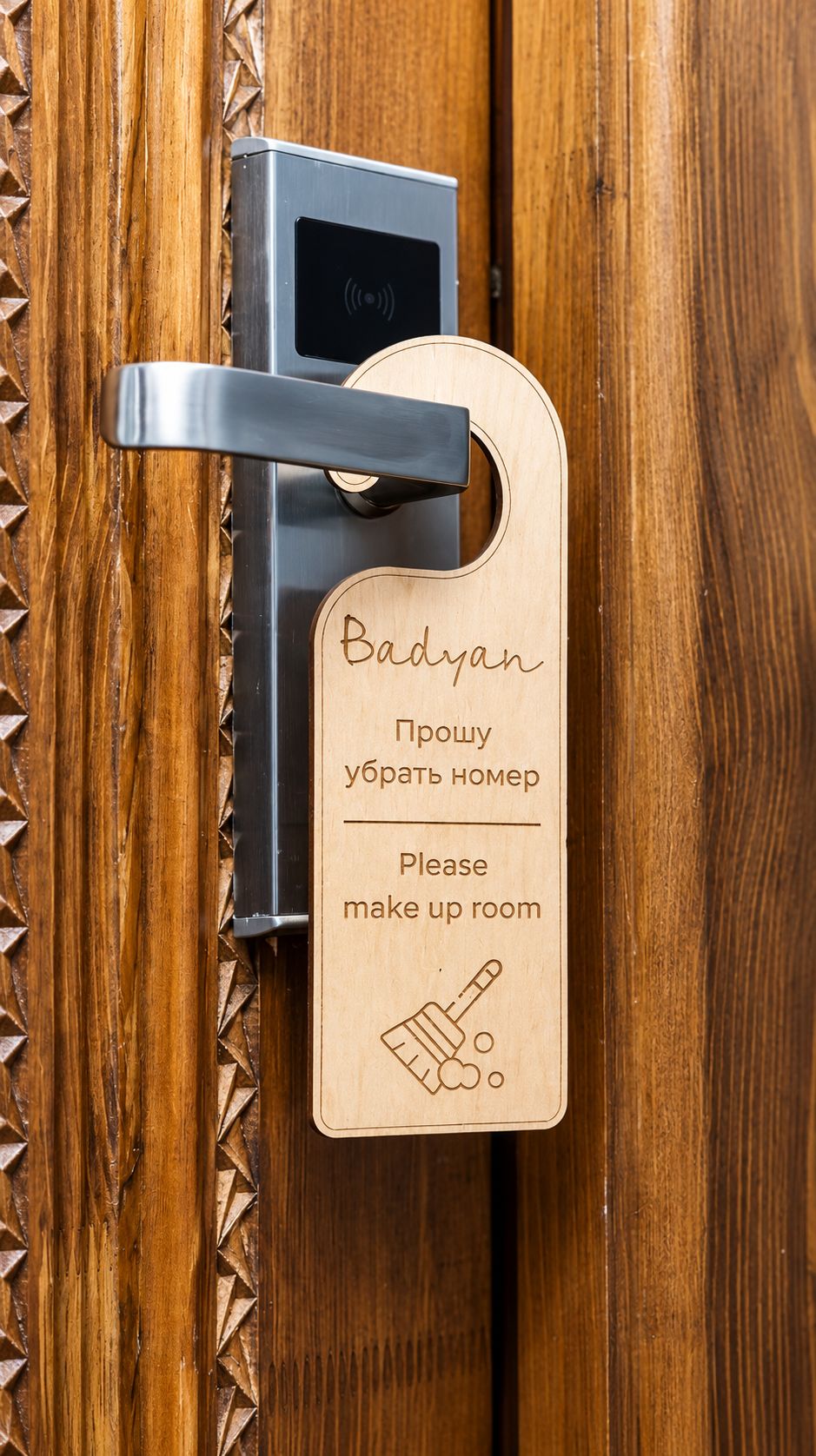 A wooden door with a metal handle and a keycard with Cyrillic text and a makeup brush icon.