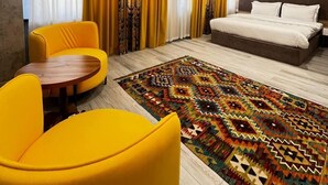 A hotel room with a bed, two yellow chairs, a patterned rug, and a large window with curtains. - Badyan Hotel (Bukhara)