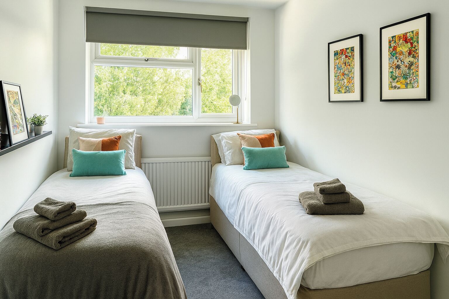 A bedroom with two single beds, a window with a view of greenery, and two framed artworks on the wall.