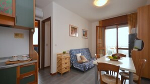 Un espacio habitable compacto con kitchenette, zona de comedor y sofá.
