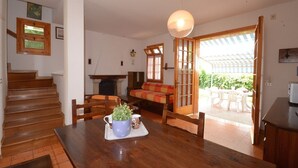 Ein Essbereich mit einem Holztisch, Stühlen, einem Blumentopf und Blick auf die Terrassenfläche.