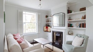 A living room with a fireplace, a sofa, a chair, and a coffee table. - Battersea Bright House | Sleeps 4 (London)