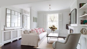 A modern living room with a sofa, armchair, coffee table, and a fireplace. - Battersea Bright House | Sleeps 4 (London)