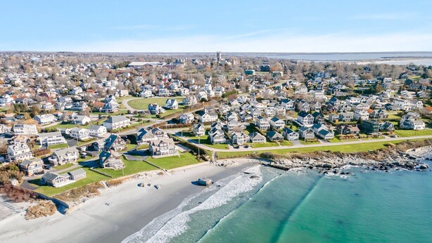 Luchtbeeld van een kustgebied met woonhuizen, een strand en een waterlichaam.
