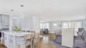 Een moderne keuken met witte kastjes, een centraal eiland en hanglampen.