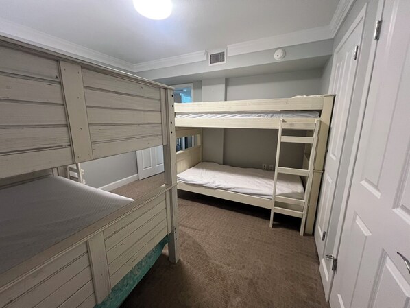 A bunk bed room with a desk and a wardrobe.