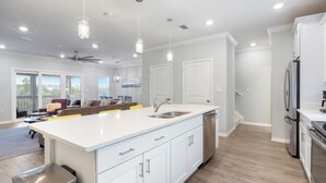 A modern kitchen with white cabinetry, a large island, stainless steel appliances, and pendant lighting.