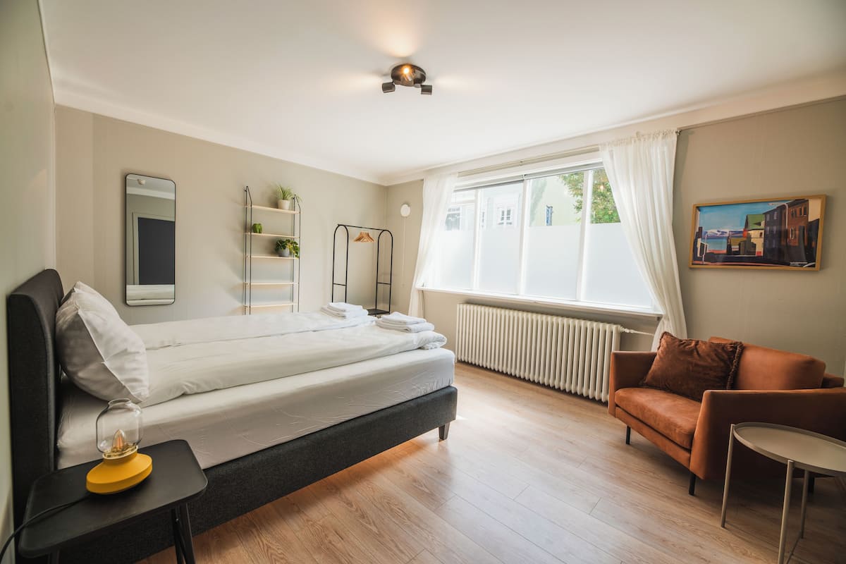 A modern bedroom with a bed, bedside table, and a window with curtains.